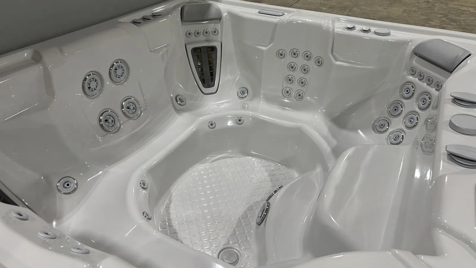 White modern hot tub with multiple jet nozzles and contoured seating inside a showroom.