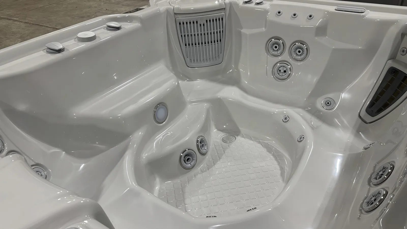 Close-up view of a clean white jacuzzi hot tub interior with multiple water jets and seating areas.