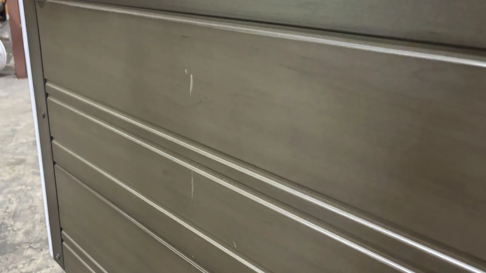 Close-up of a gray metal garage door with horizontal panels and slight scratches on surface.