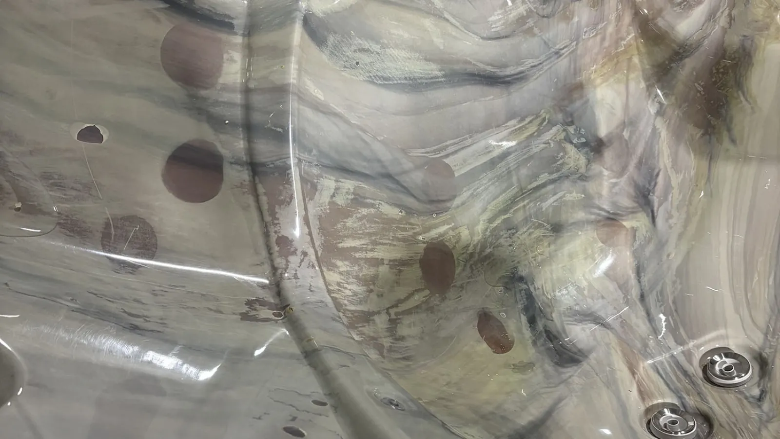 Glossy marbled hot tub interior with built-in jets and contoured seating under ambient lighting.