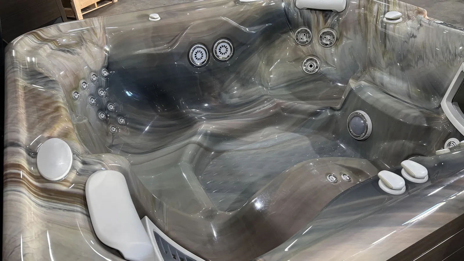 Modern gray marble-patterned hot tub with multiple jets, padded headrests, and ergonomic seating.