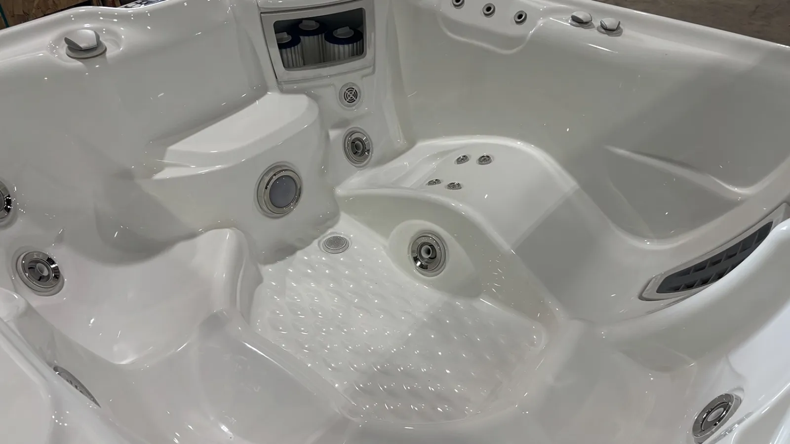 White modern hot tub interior with built-in seats, water jets, and filters in a clean setting.