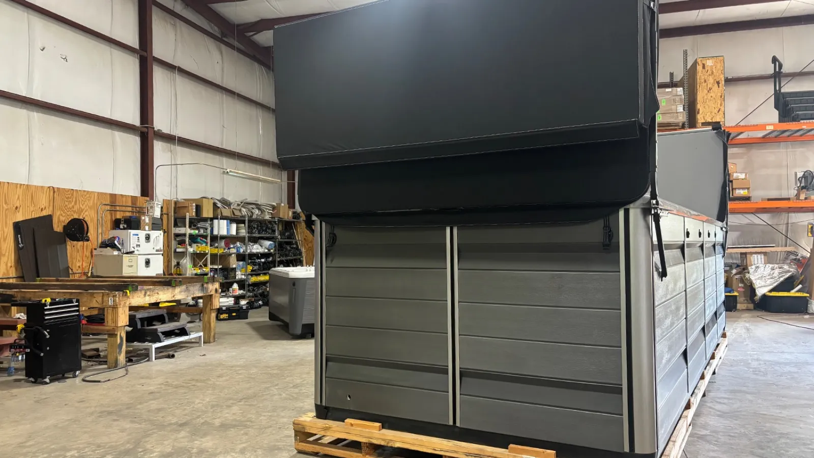 Large gray and black industrial container in warehouse with wooden pallet and shelves in the background