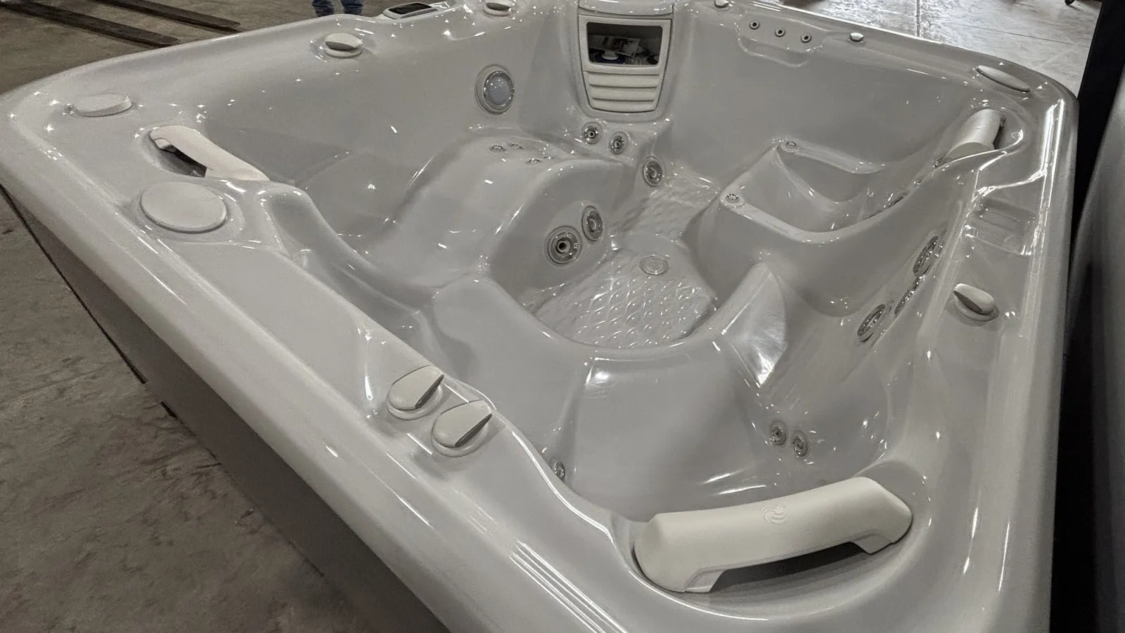 White luxury hot tub with multiple jet controls and ergonomic seating for relaxation in an indoor setting.