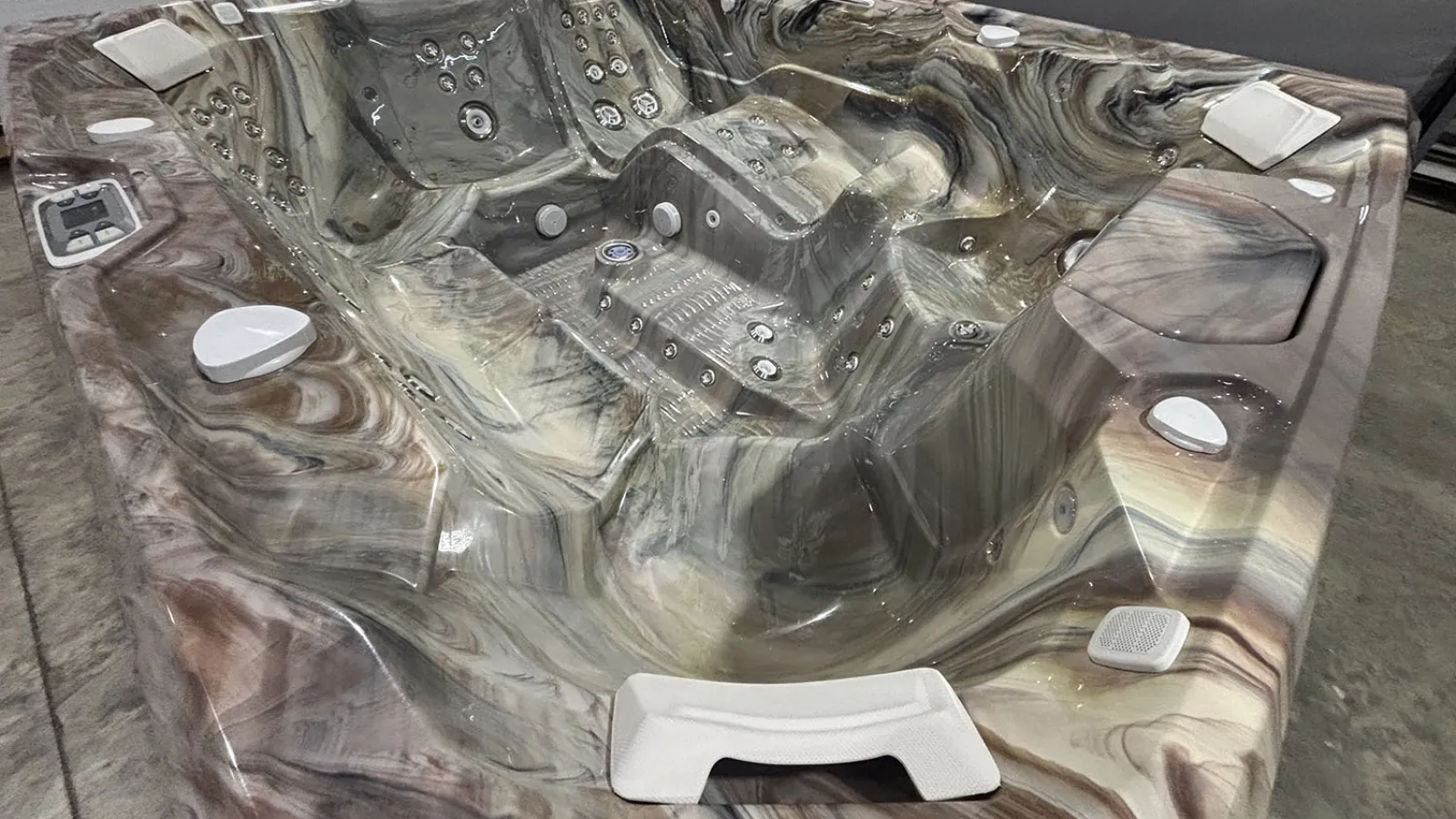 Marble-patterned multi-seat hot tub with white jets and control panel in an indoor setting.