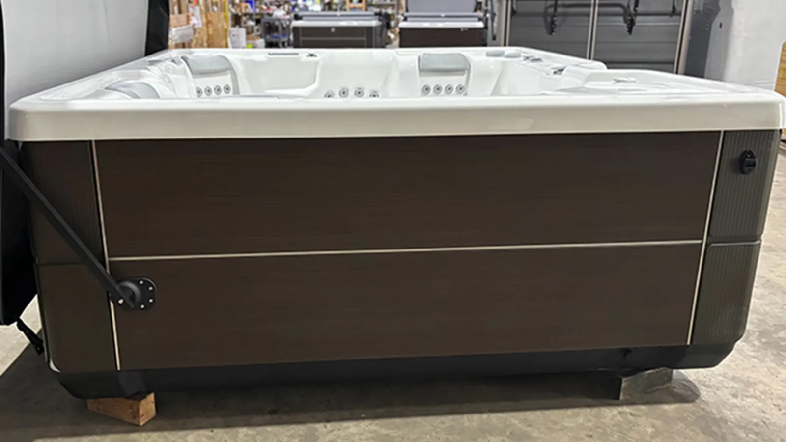 Modern rectangular hot tub with white interior and dark brown exterior panels in showroom.