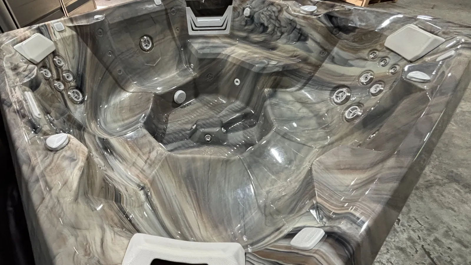 Luxury marble-patterned hot tub with multiple jets and ergonomic seating in a showroom setting