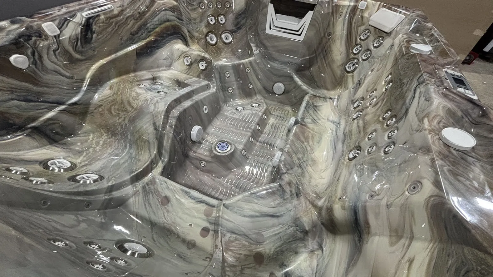 Luxury marble-patterned hot tub with multiple jets, ergonomic seating, and built-in headrests indoors.