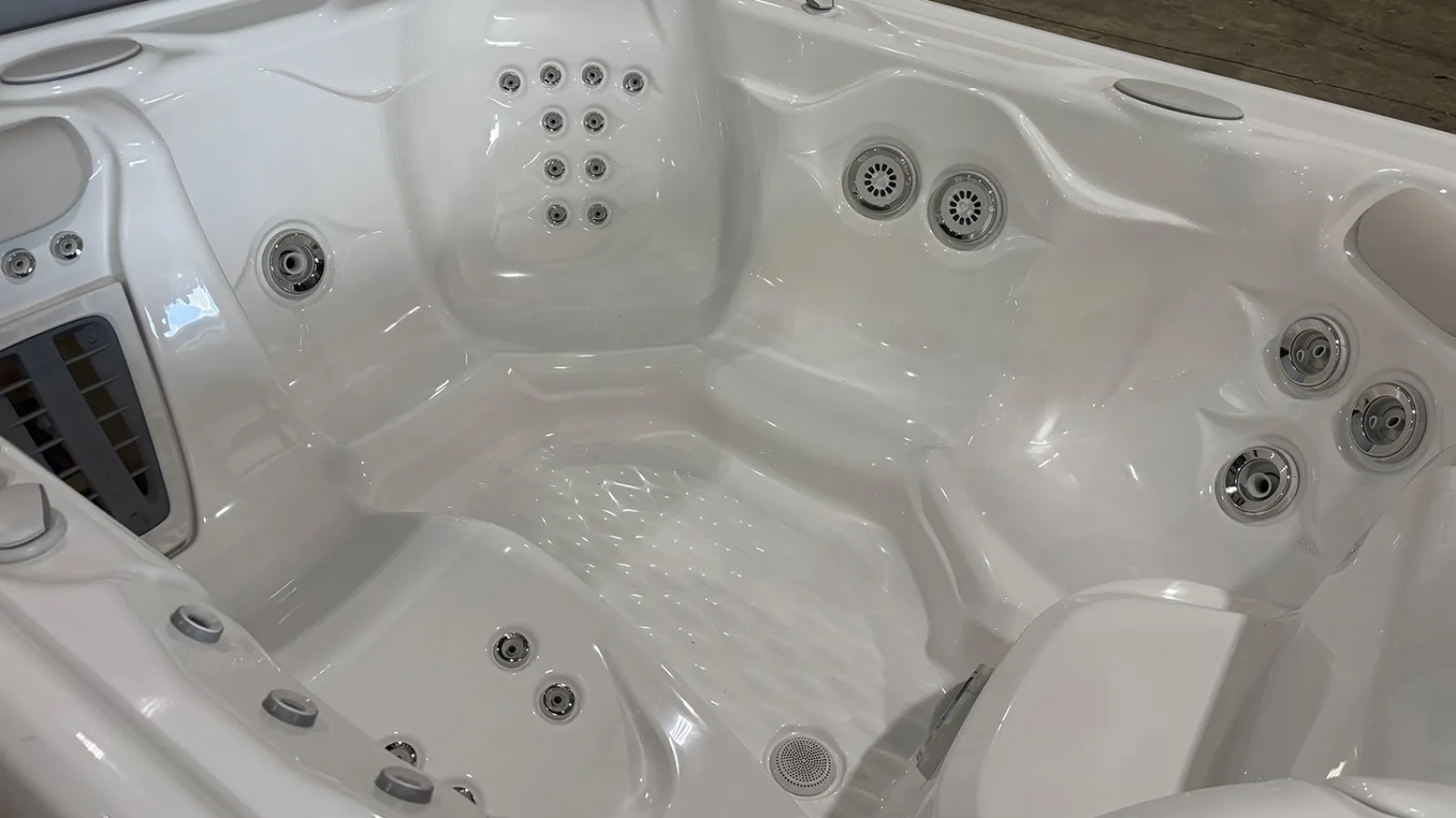 White luxury hot tub with multiple jet nozzles and ergonomic seating inside a wooden deck area.