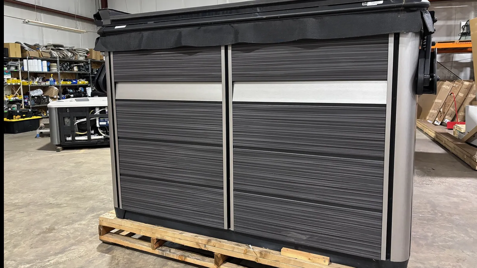 Modern outdoor kitchen island with dark wood panels and silver accents in a warehouse setting.