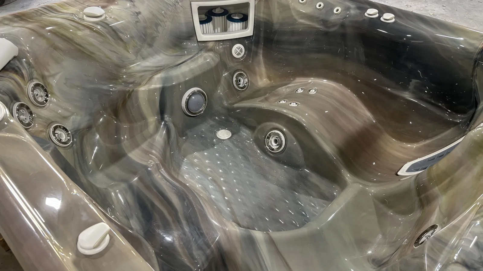 Empty luxury hot tub with multiple built-in jets and contoured seats in a marbled gray finish.