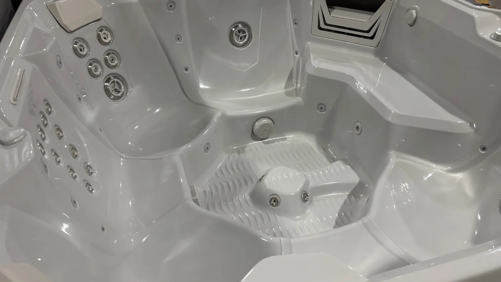 Interior view of a white luxury spa hot tub with multiple seating and jet nozzles for relaxation.