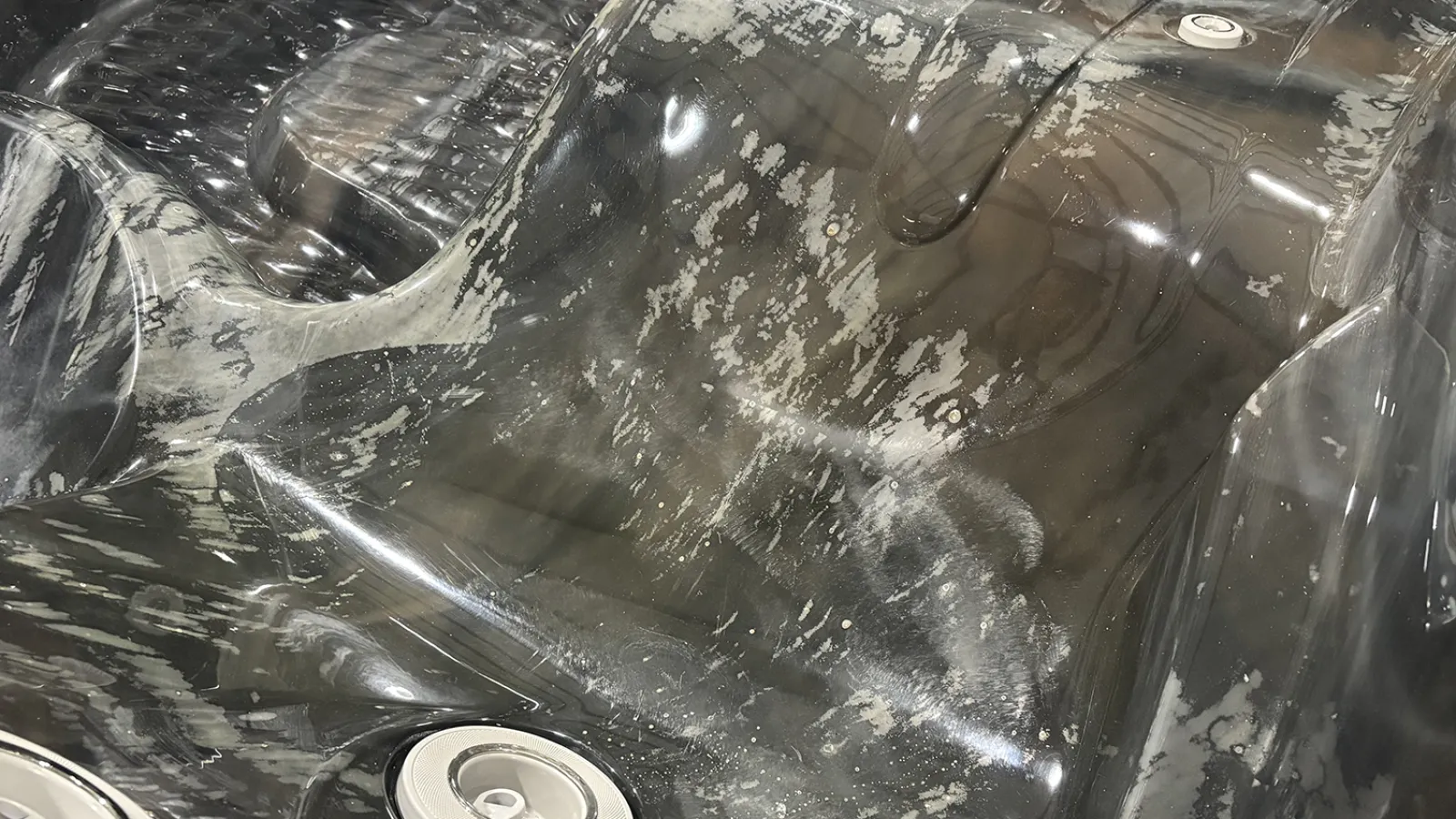 Close-up of a textured black and gray hot tub seat with integrated jets and armrests.