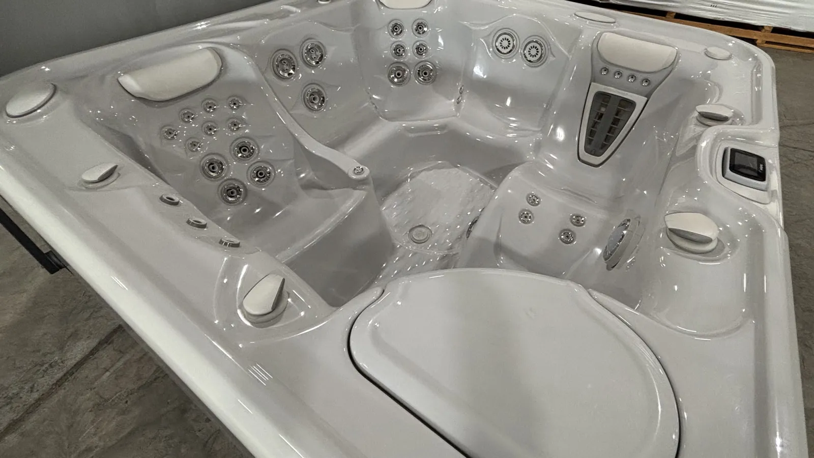 Modern white hot tub with multiple jet nozzles, ergonomic seating, and headrests in an indoor setting