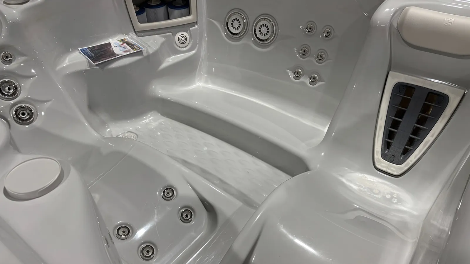 Modern white hot tub interior with multiple massage jets and ergonomic seating for relaxation and hydrotherapy.