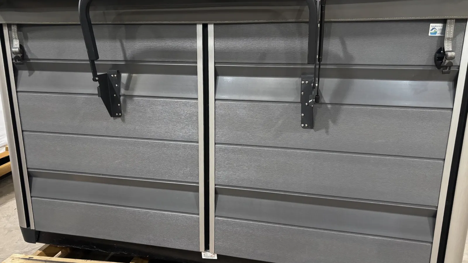 Close-up of a modern gray sectional garage door with horizontal panels and metal hardware.