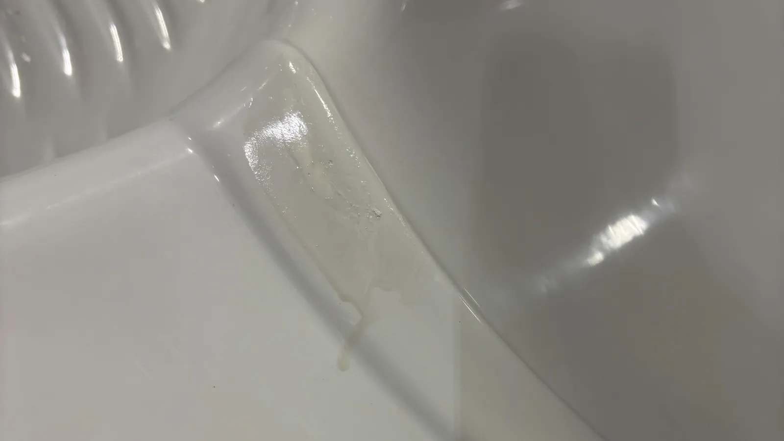 Close-up of a clear adhesive tape on a glossy white plastic surface with subtle reflections.