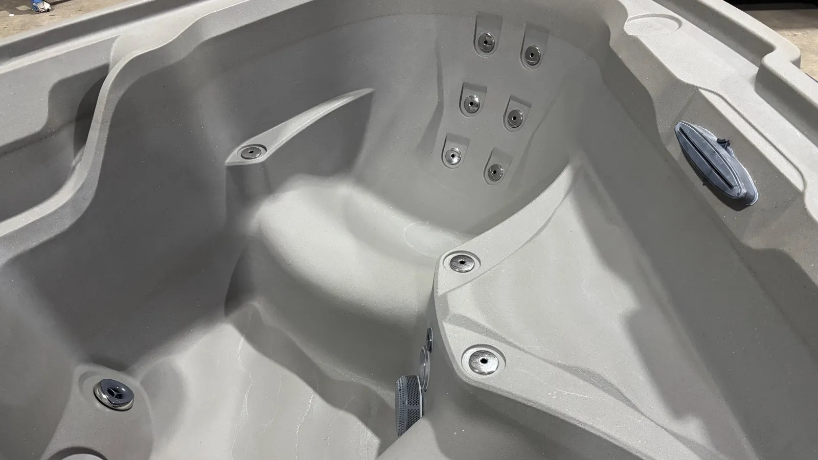 Empty gray spa tub with multiple water jets and contoured seating for relaxation and hydrotherapy.
