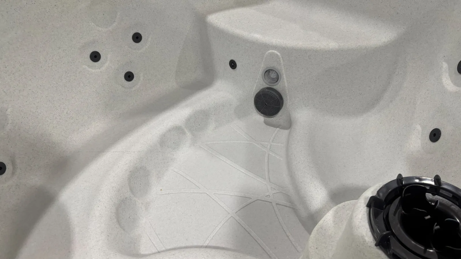 Close-up of a white spa tub interior with seating, jets, and textured bottom surface.