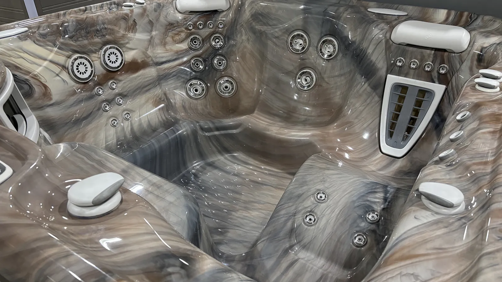 Close-up of a modern marble-patterned hot tub interior with multiple jet nozzles and headrests