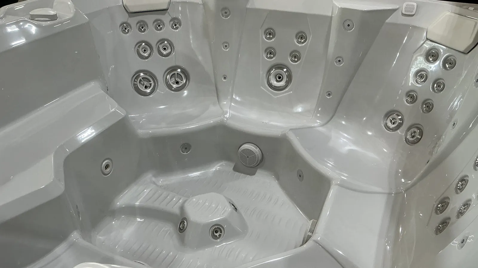 Close-up of a white modern hot tub interior with multiple water jets and contoured seats.