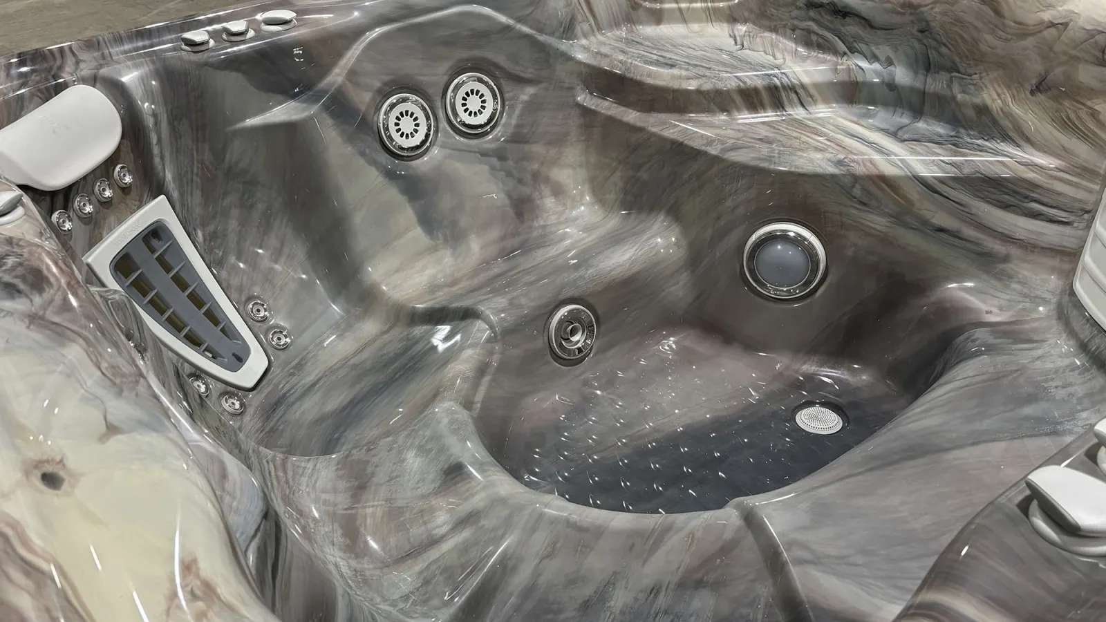 Close-up of a modern marble-patterned hot tub interior with multiple jets and contoured seating.