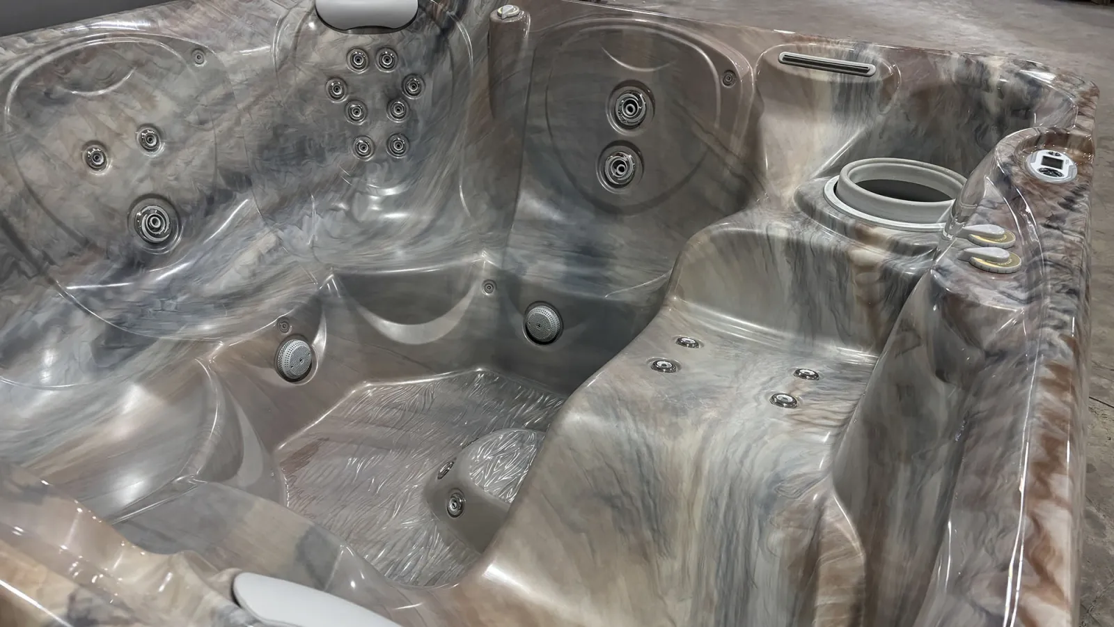 Close-up of an empty marble-textured hot tub with multiple jets and ergonomic seating