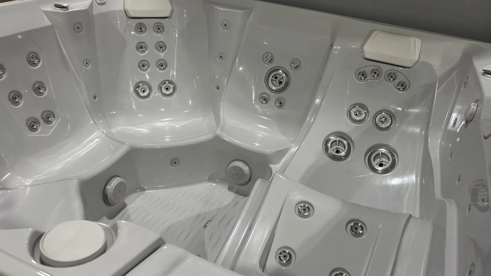 White modern hot tub interior with multiple hydrotherapy jet nozzles and headrests for comfort and relaxation.