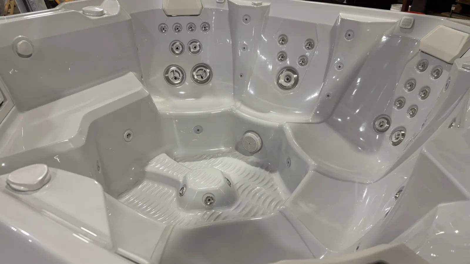 White modern hot tub with multiple jet nozzles and built-in seating for relaxation and hydrotherapy.