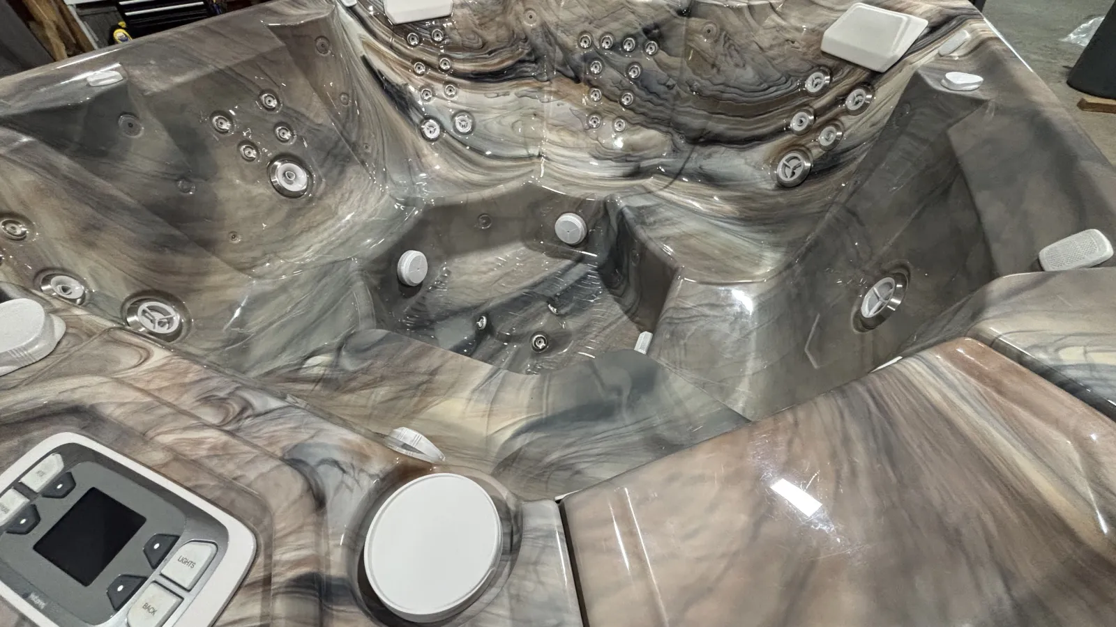 Close-up of a modern marble-effect hot tub interior with multiple jets and control panel visible.