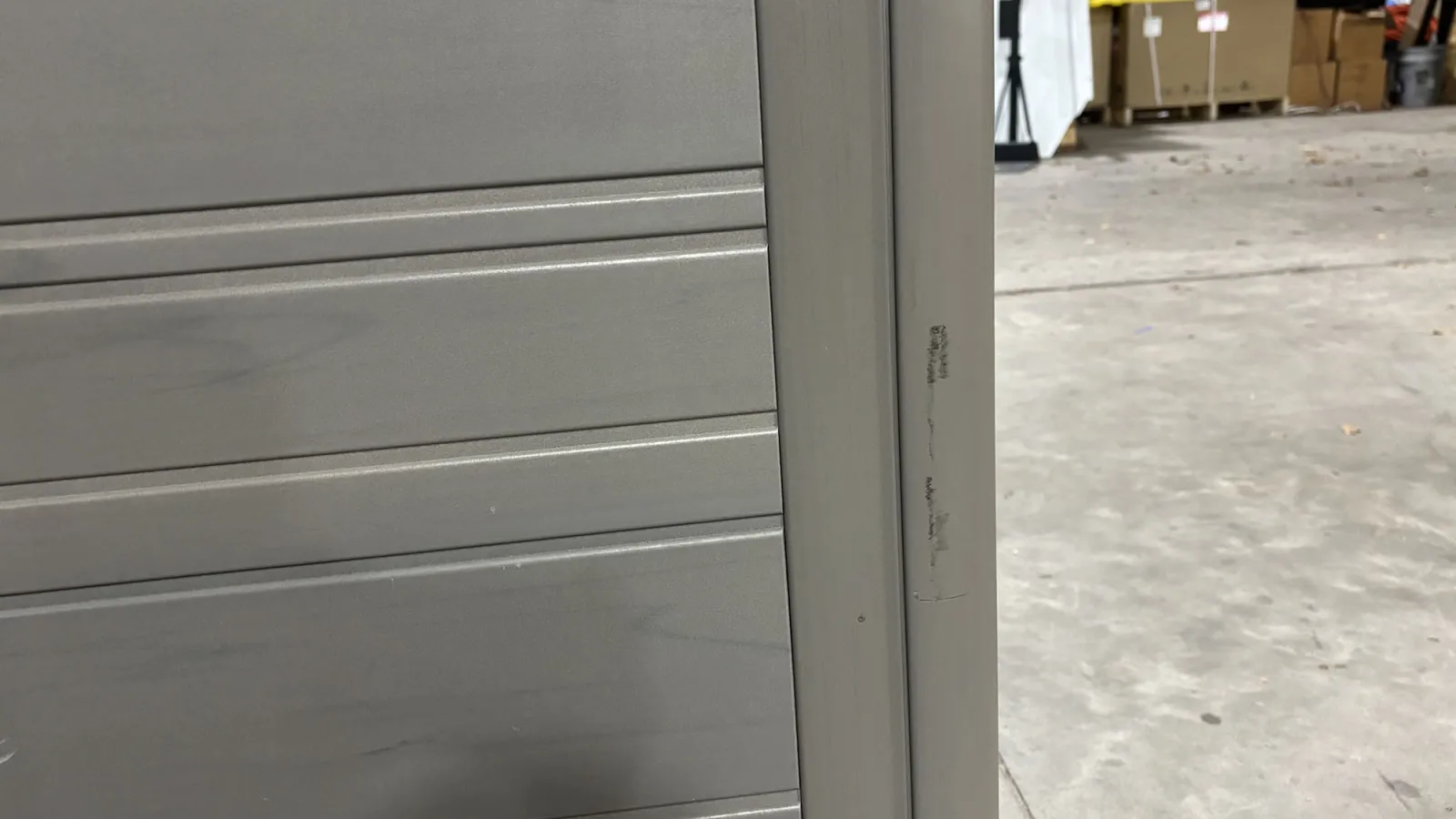 Close-up of a gray metal garage door with horizontal panels in a warehouse setting.