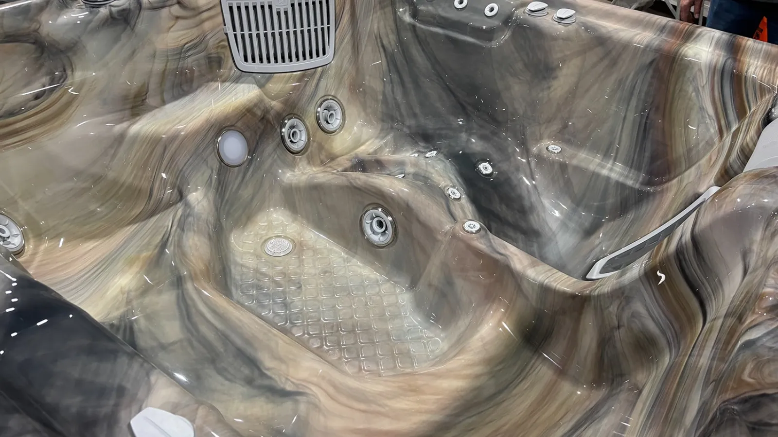 Close-up of a marbled brown and gray luxury hot tub interior with multiple jet nozzles and textured floor.