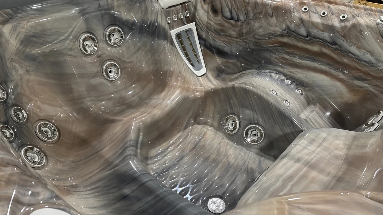Modern gray marble-patterned hot tub with multiple jet nozzles and ergonomic seating designed for relaxation.