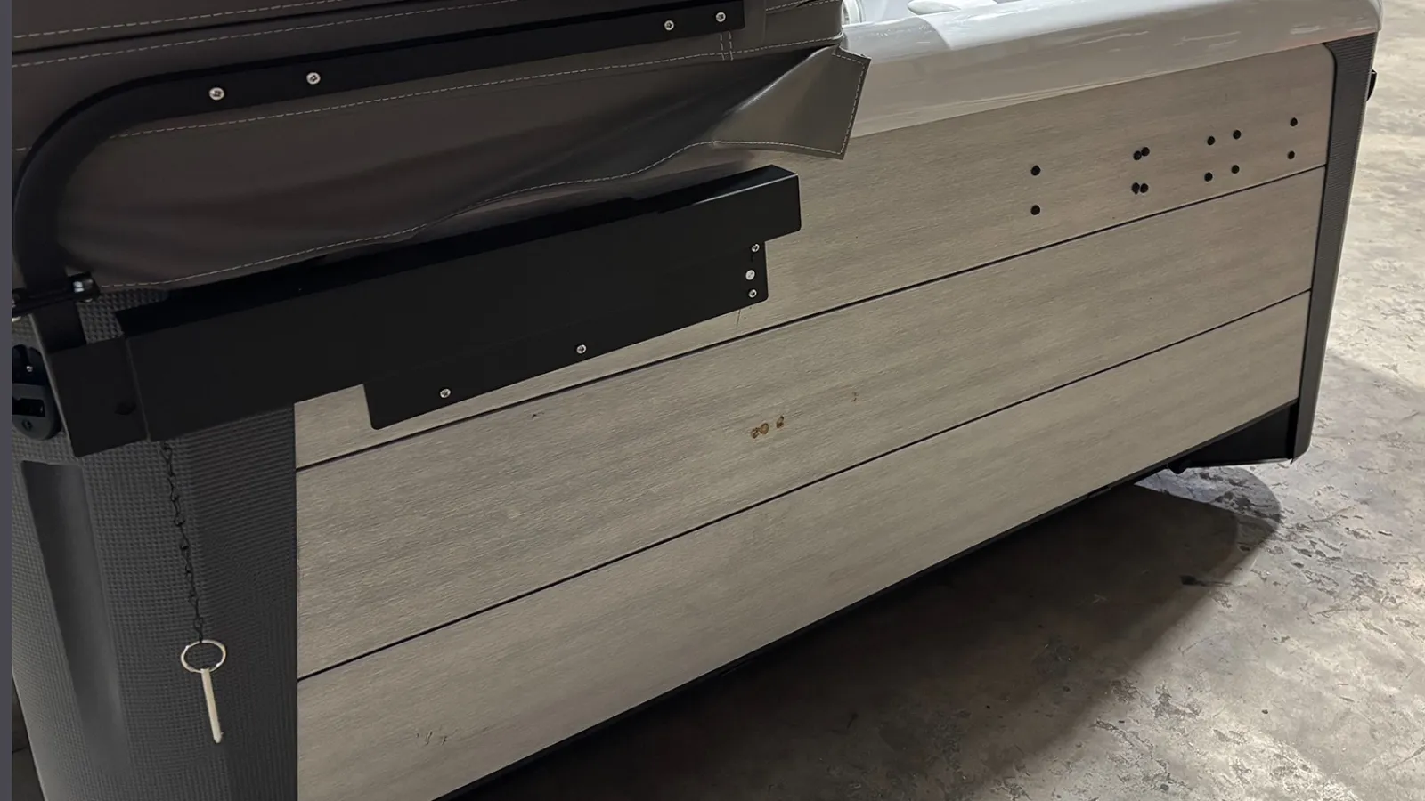 Side view of a pool table showing wooden paneling, brown leather cushion, and a metal key hanging on a chain