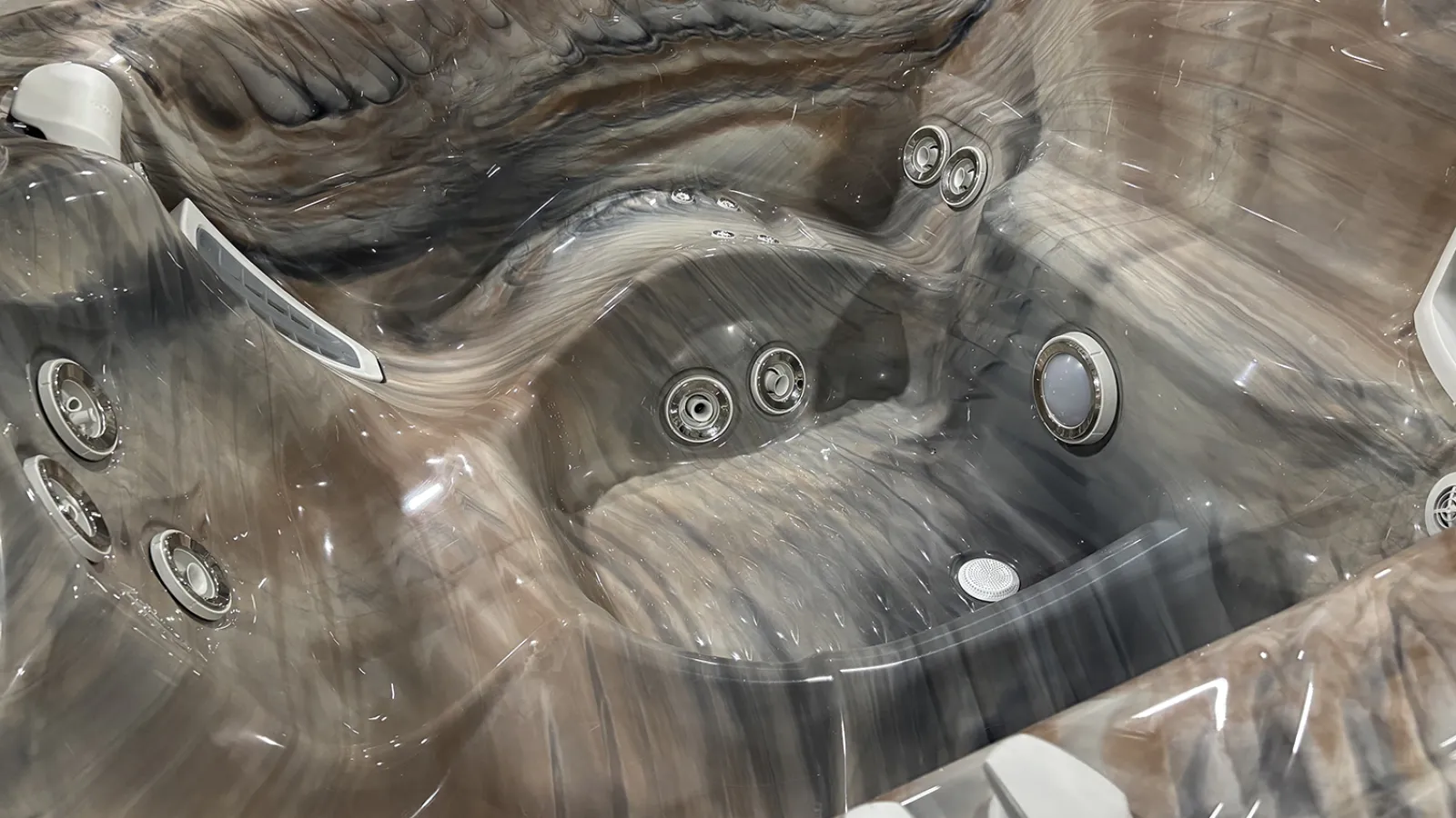 Close-up of a modern hot tub with multiple adjustable water jets and ergonomic seats in a marbled finish.