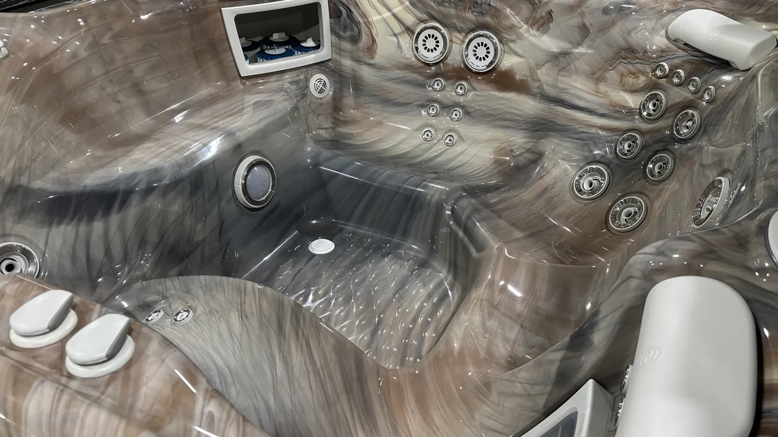 Empty luxury hot tub with multiple jets and ergonomic seating featuring marbled brown and gray finish.