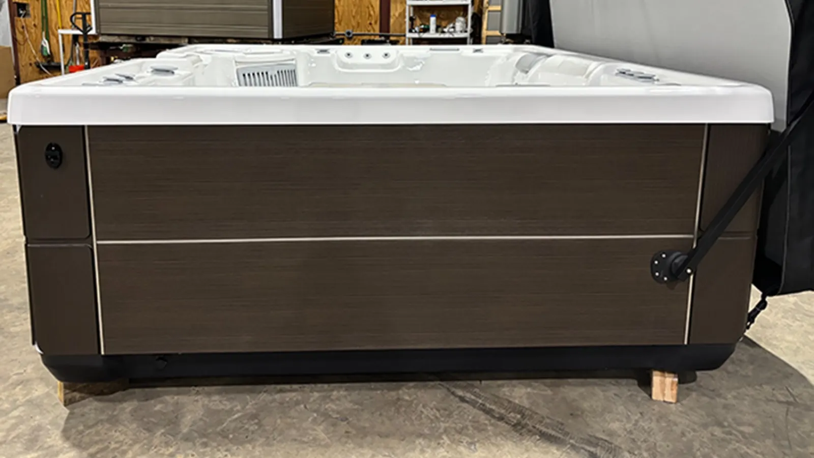 Modern rectangular hot tub with white interior and dark wood exterior panels in a showroom setting.