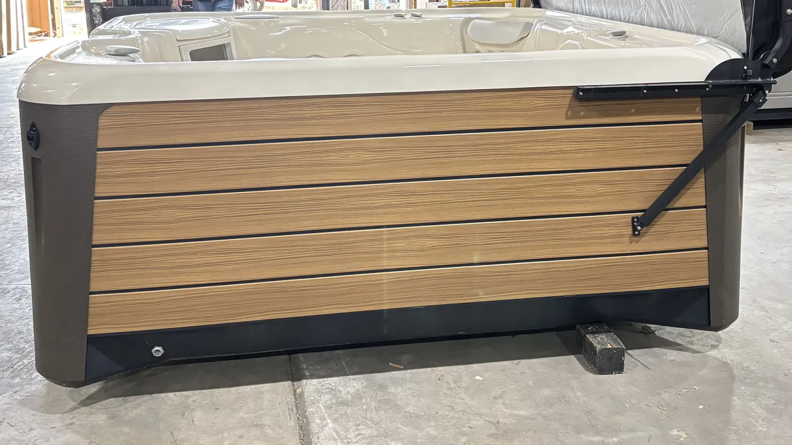 Modern outdoor hot tub with wooden paneling and beige interior set on concrete floor indoors