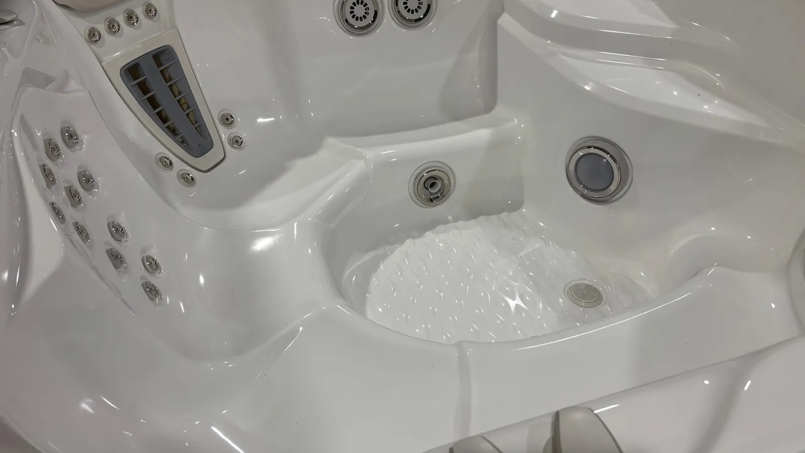 Close-up of a white jacuzzi interior showing multiple water jets and ergonomic seating areas.