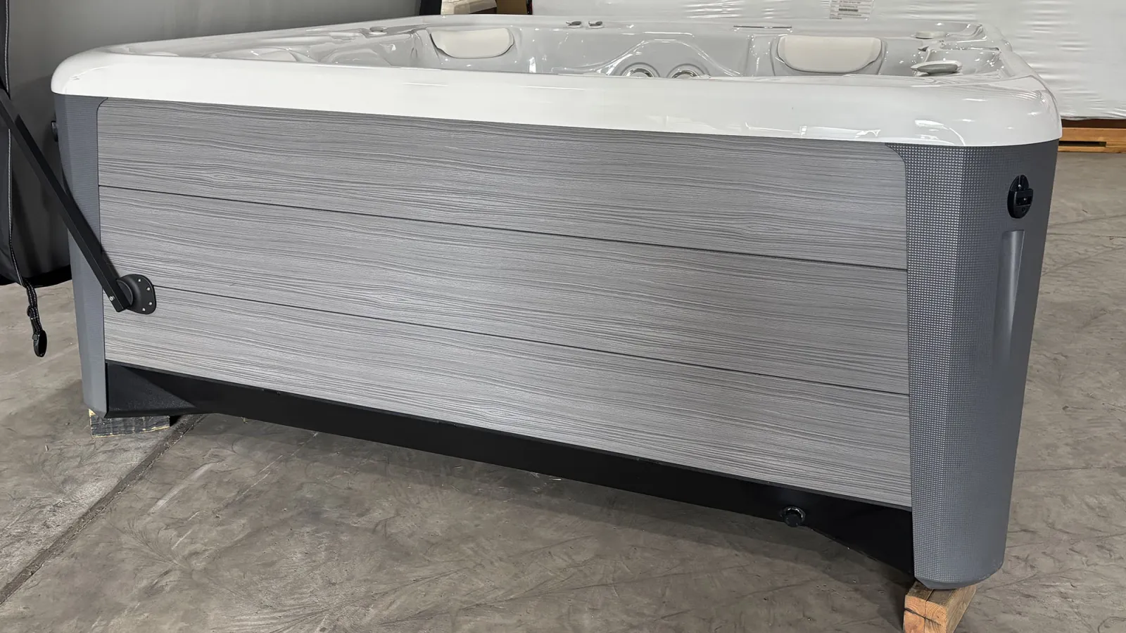 Gray and white outdoor spa hot tub with textured sides on concrete floor in warehouse setting