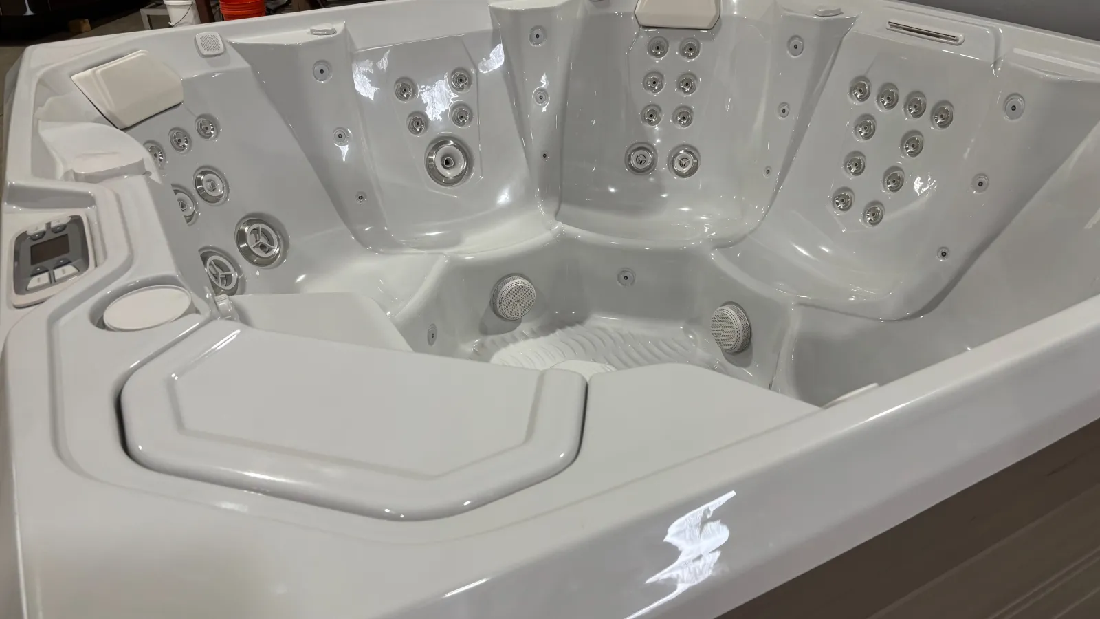 White multi-seat hot tub with multiple jets and built-in headrests in a showroom setting