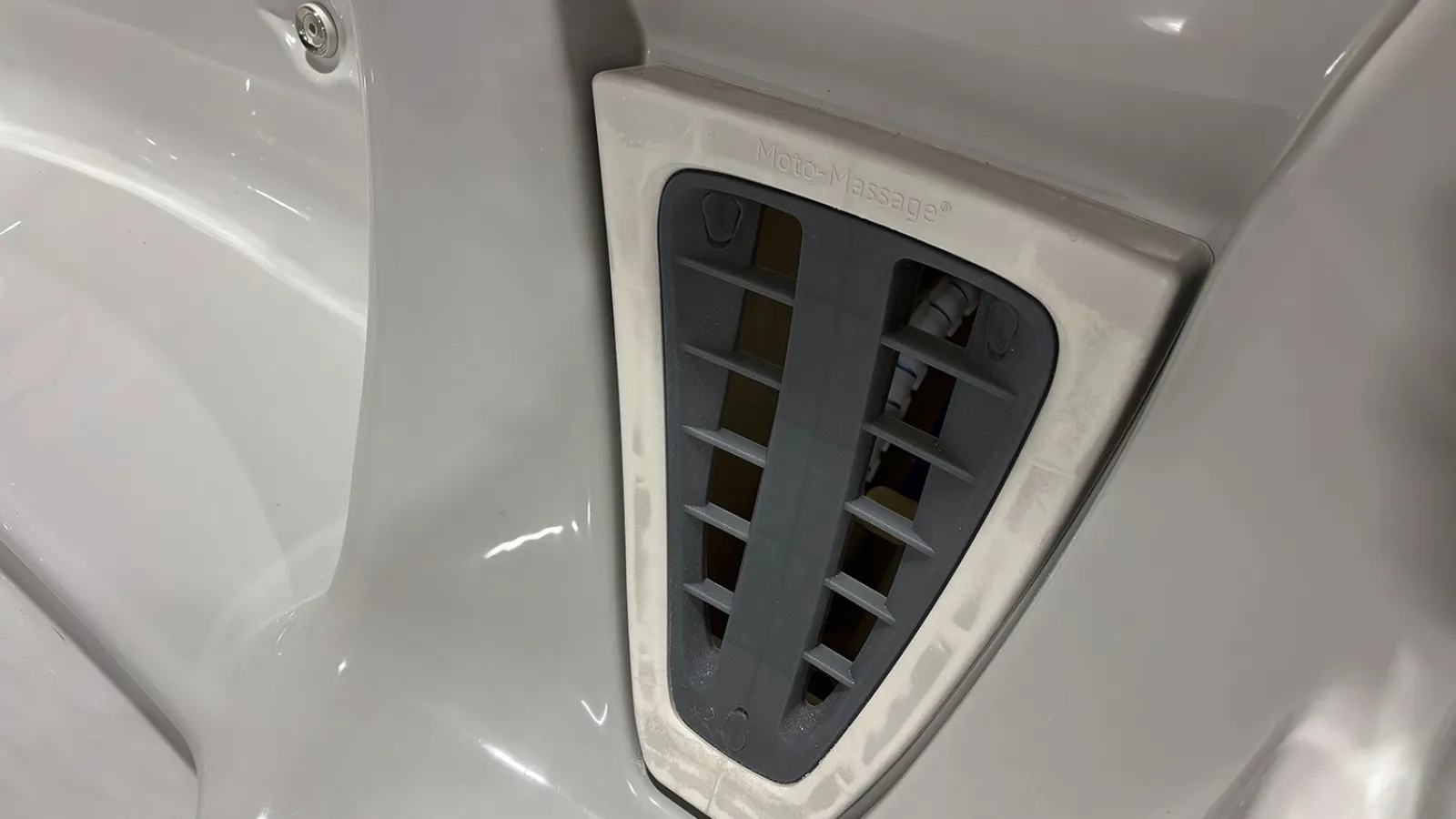 Close-up of a white hot tub corner featuring a grey water jet labeled Hydro Massage with adjustable vents.