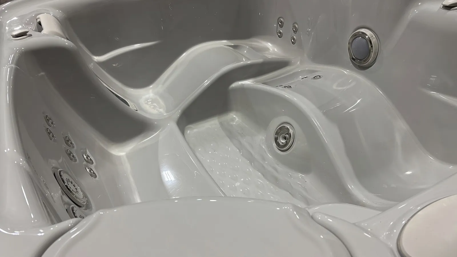 Close-up of empty white jacuzzi tub with built-in seats and multiple water jets for hydrotherapy relaxation.