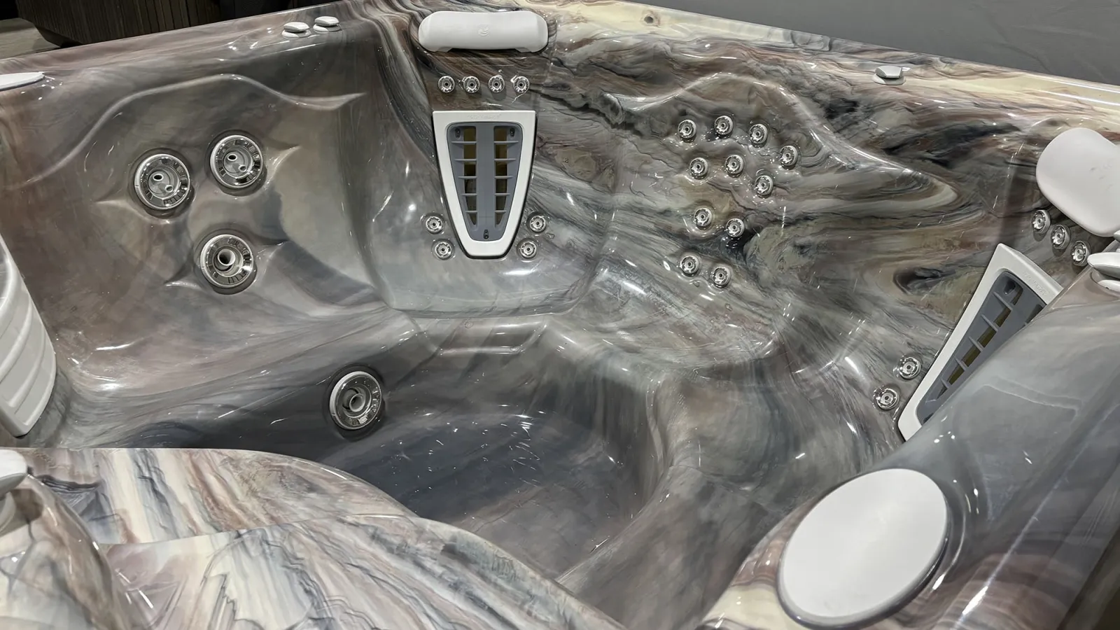 Close-up of a luxury marble-patterned hot tub interior with multiple jet outlets and headrests.