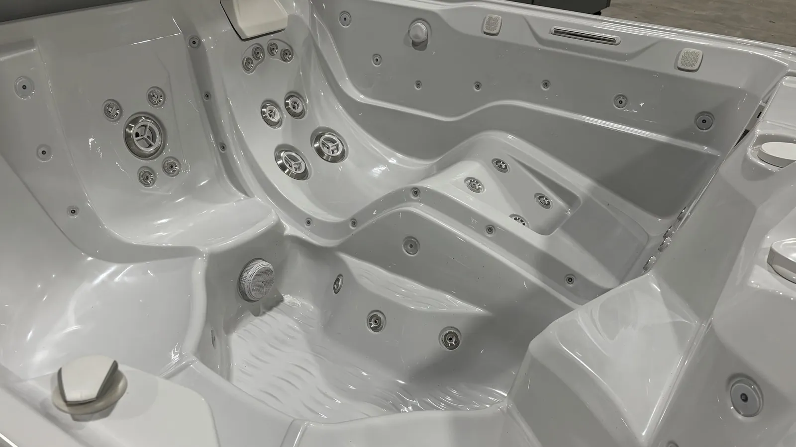 White luxury spa hot tub with multiple ergonomic seats and numerous water jets for hydrotherapy massage.