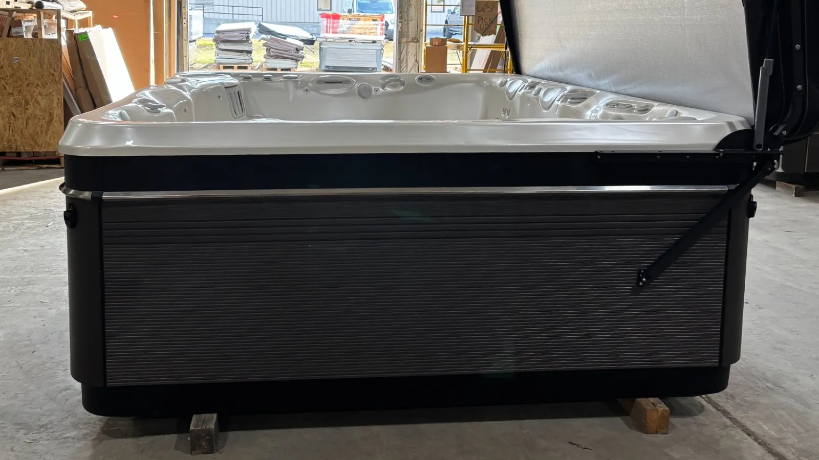 Modern hot tub with white interior and dark textured exterior in a warehouse setting under natural light