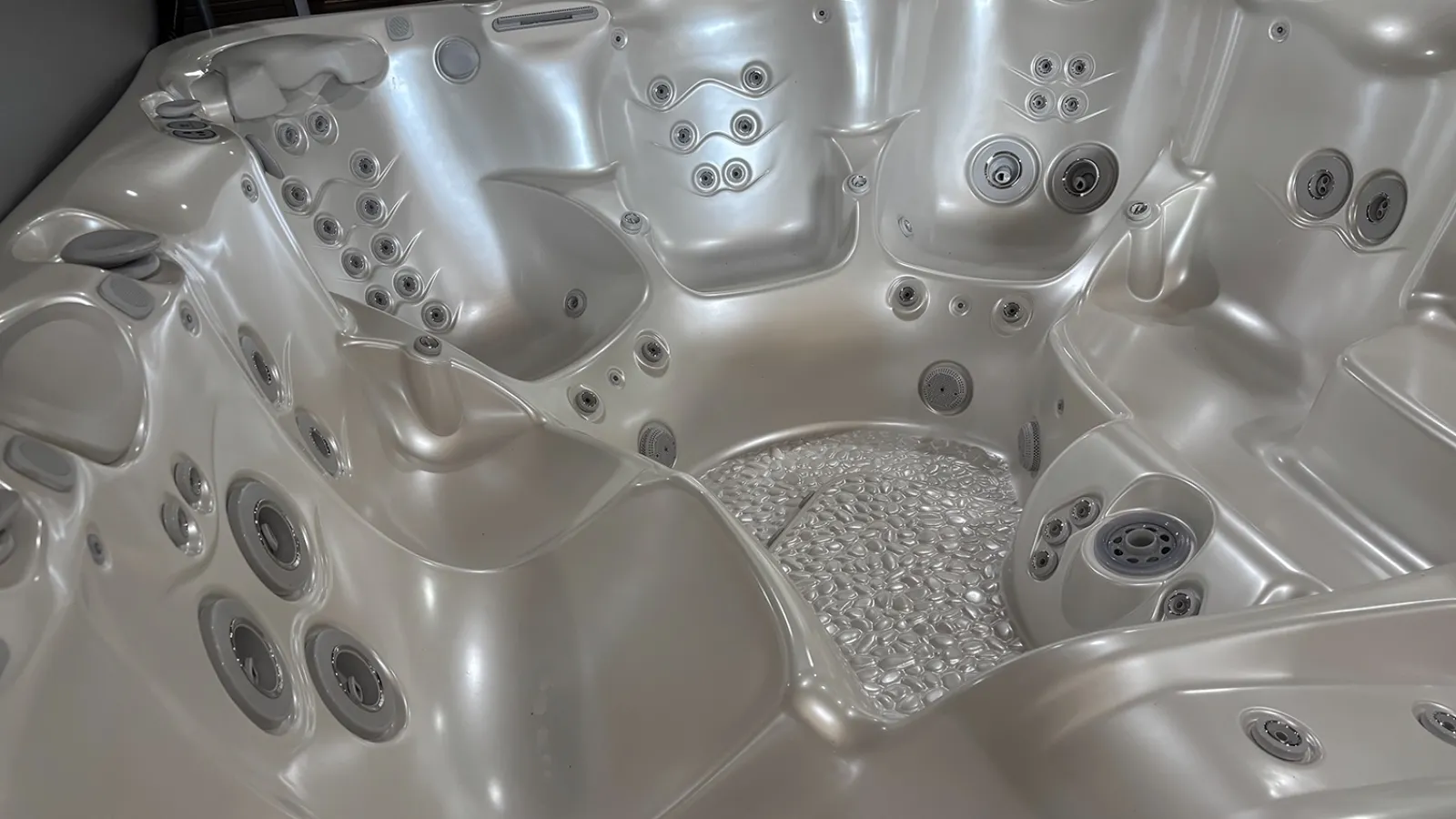 Interior view of a large silver hot tub with multiple jet nozzles and ergonomic seating