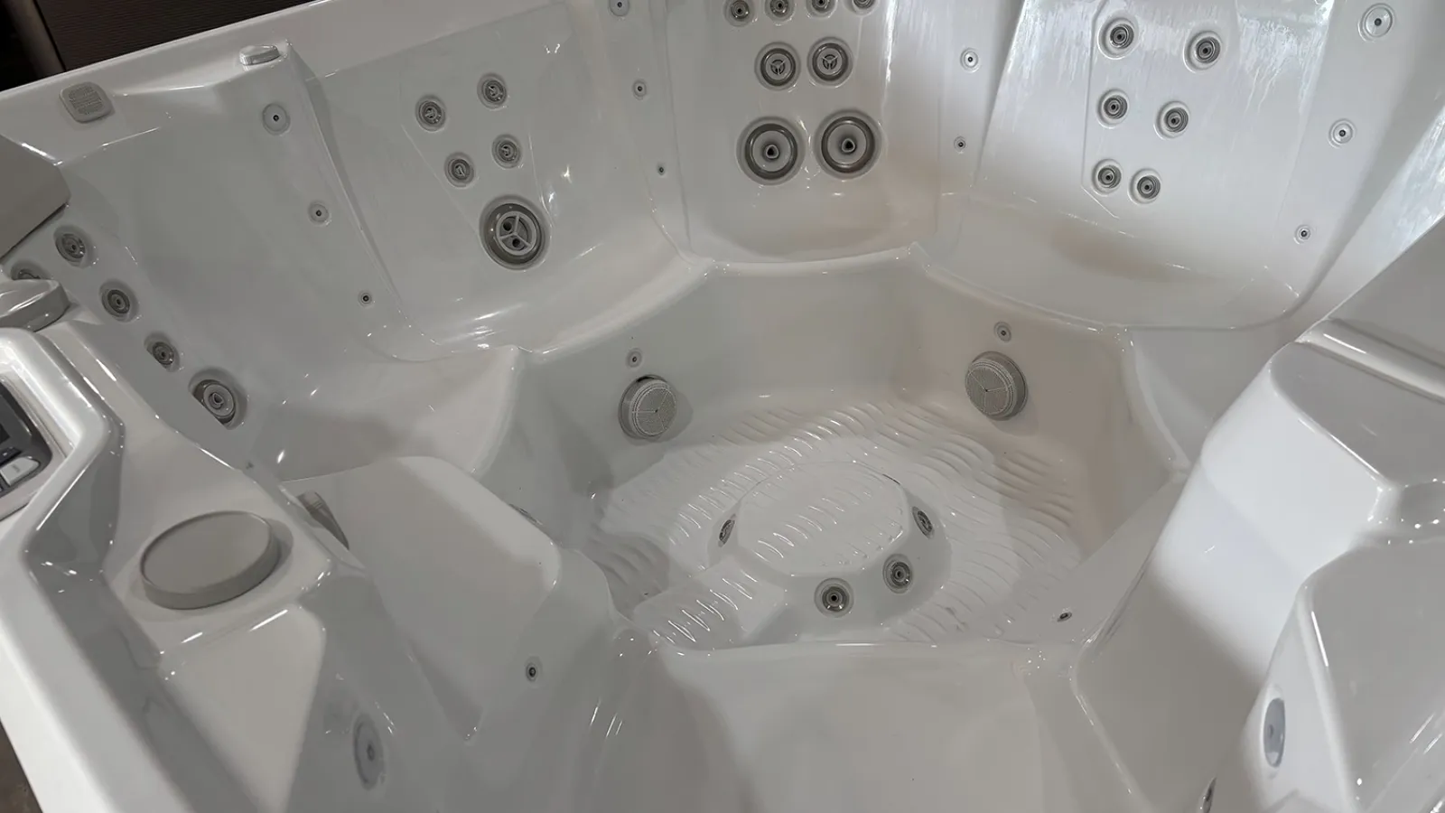 White empty jacuzzi tub with multiple jet nozzles and contoured seating for relaxation and hydrotherapy.