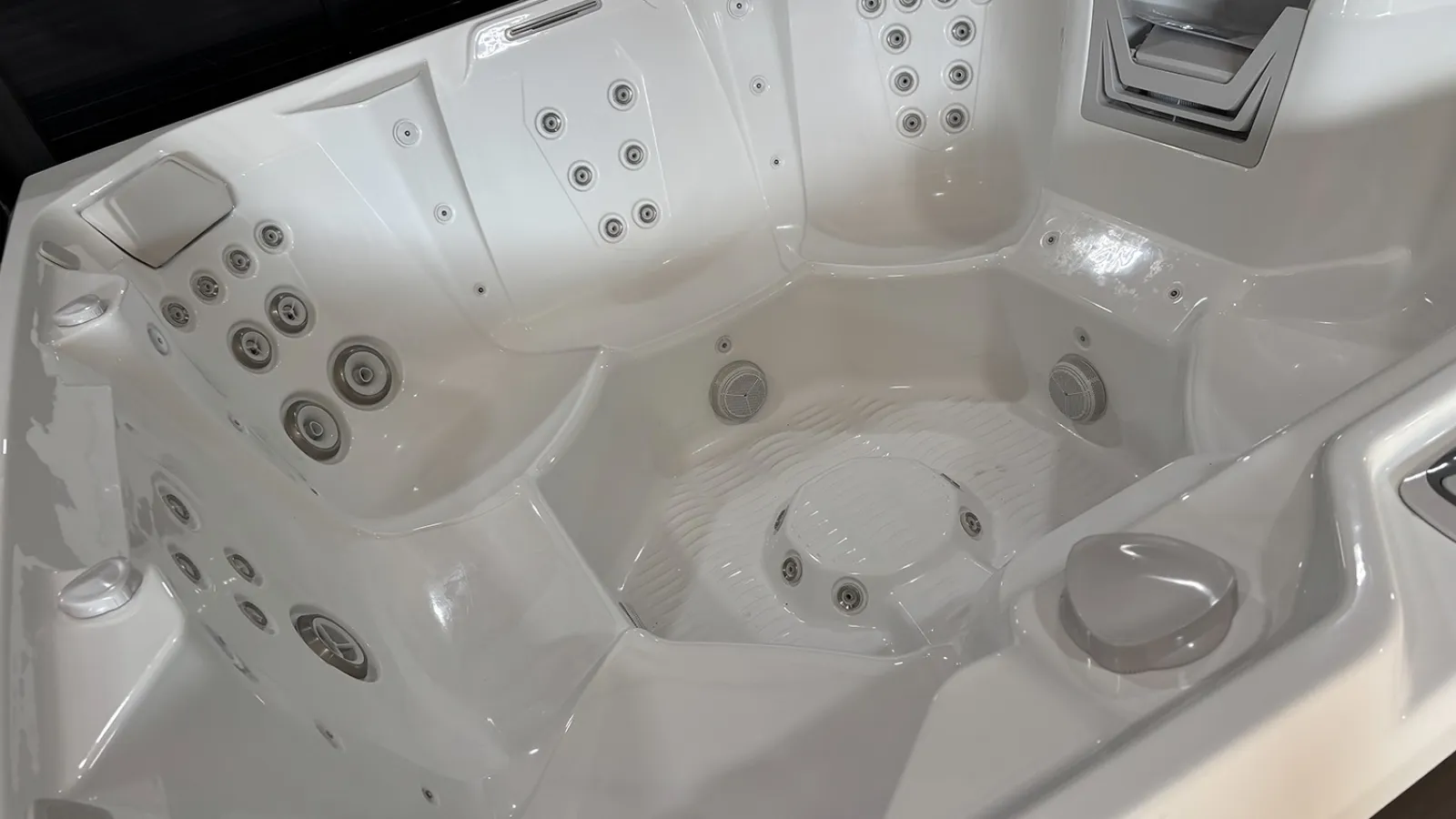 White multi-seat hot tub with numerous water jets and ergonomic seating designed for relaxation and hydrotherapy.