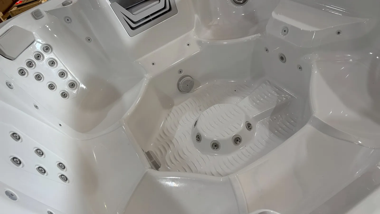 White acrylic hot tub interior with multiple seats and numerous built-in water jets for hydrotherapy.